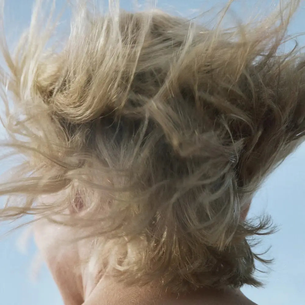 Cheveux blonds soufflés par le vent avec Après shampoing liquide bouleau, soin capillaire parfaitement adapté aux cuir chevelu