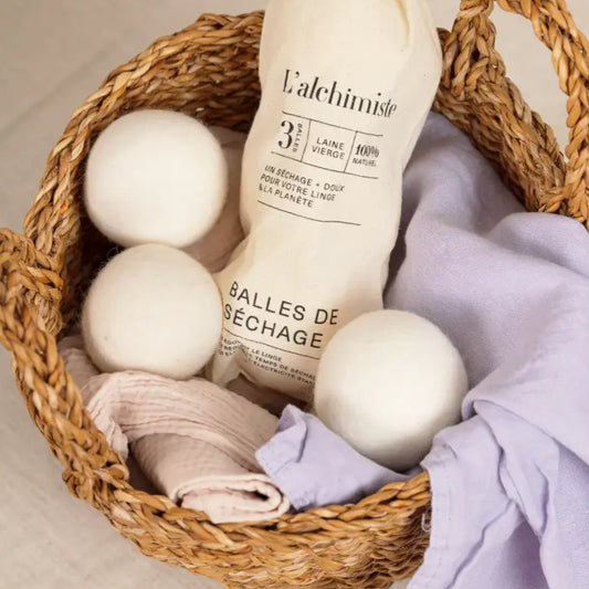 Panier en osier avec des balles de séchange en laine blanche pour un séchage écologique