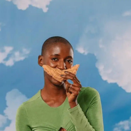 Person avec tête rasée en vert tenant un mustache en biscuit, style clin d’œil chaussettes croissant