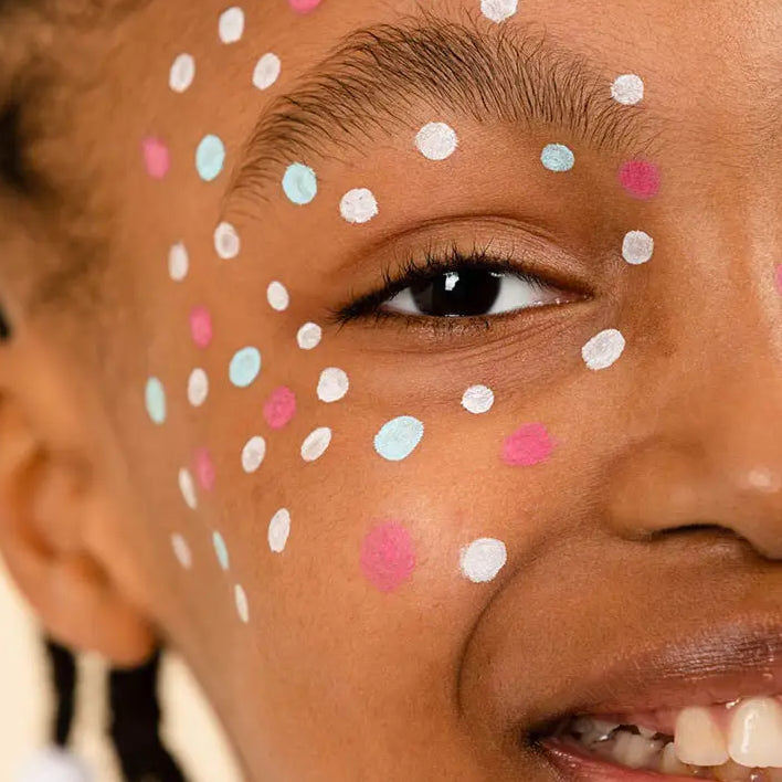 Visage d’enfant avec tatouage temporaire bleu à pois colorés, pour une consommation plus responsable