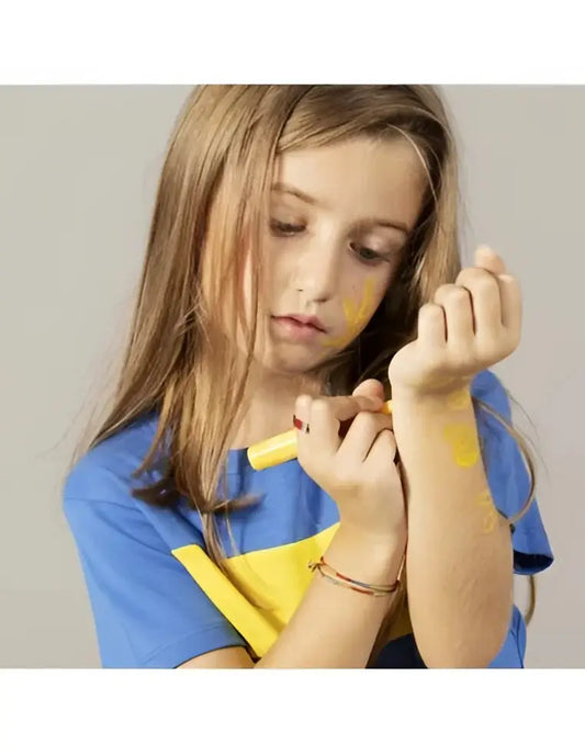 Fille enfant dessine tatouage temporaire jaune sur bras avec crayon