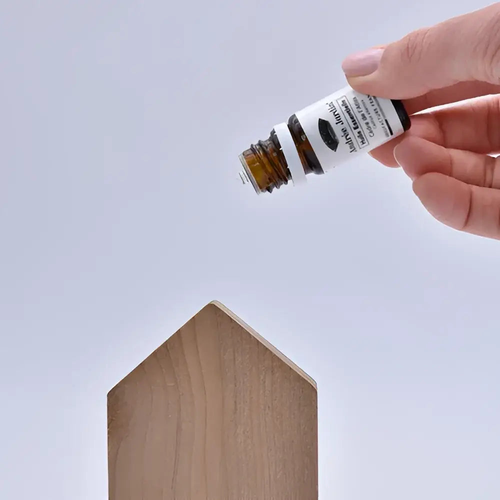 Main de cèdre Maisons anti-mites versant gouttes d’huile essentielle sur bloc bois maison au design épuré
