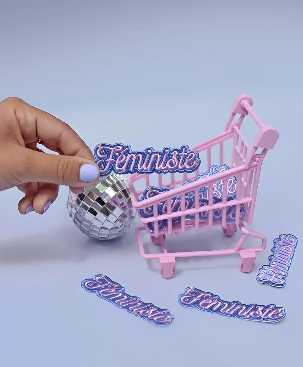 Mini panier rose rempli d’écussons féministes colorés et détails scintillants