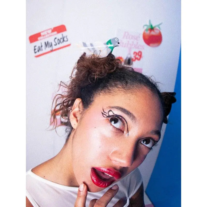 Femme aux cheveux pigeon en deux chignons, eyeliner noir dramatique et rouge à lèvres, pince à cheveux design créatif