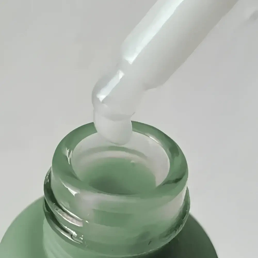Goutte de serum visage peau grasse dans une bouteille verte pour aux imperfections