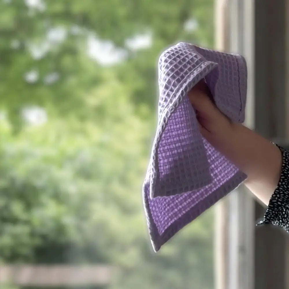 Main tenant tenant d’une microfibre violette pour spray nettoyant vitres et surfaces vitrées