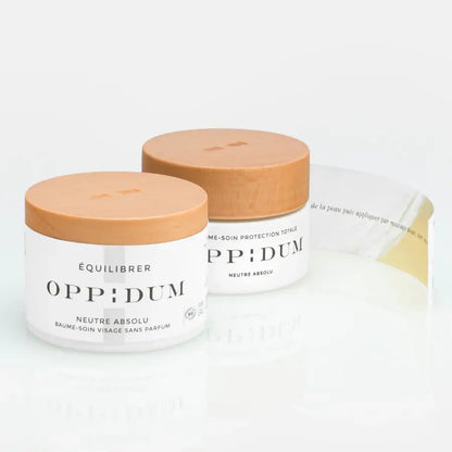 Deux pots blancs avec couvercles beige pour Baume Neutre Absolu soin et protection