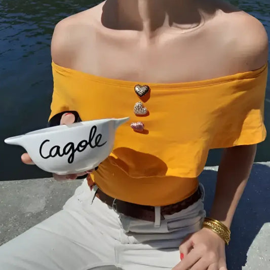 Person en top jaune et pantalons blancs tenant un bol breton revisité Cagole