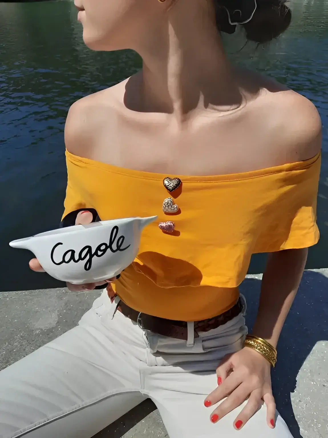 Personne en top jaune et pantalon blanc tenant bol breton cagole revisité