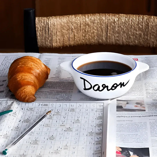 Bol breton daron en céramique blanche à liseré bleu, rempli de liquide foncé