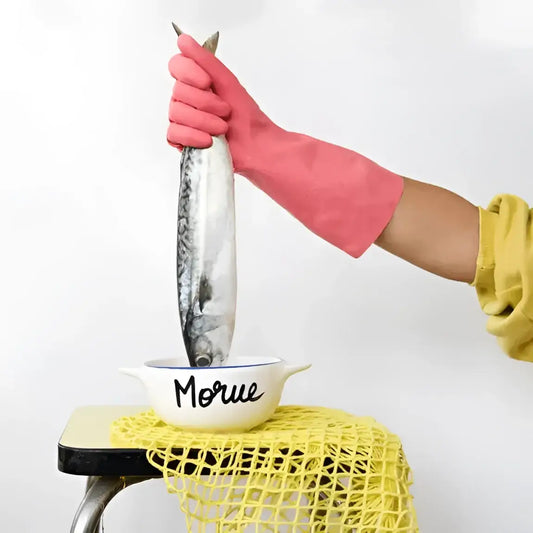 Main rose tenant un poisson au-dessus d’un bol Breton Morue artisanal