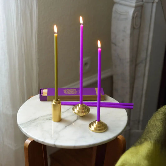 Trois bougies fines allumées en porte-bougies en laiton massif années folles