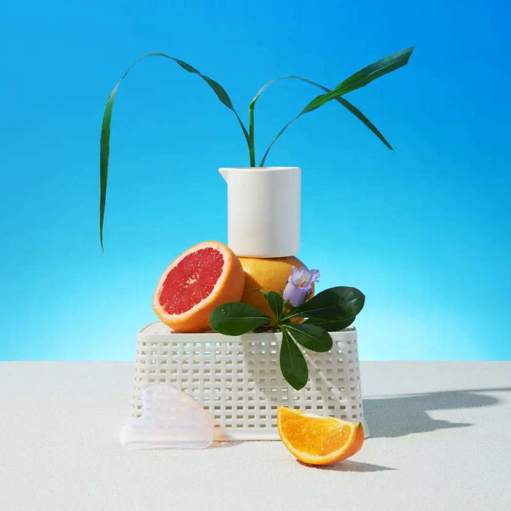 Bougie de massage avec pierre gua sha : pitcher blanc, feuilles vertes, pamplemousse, citron, fleur violette, orange