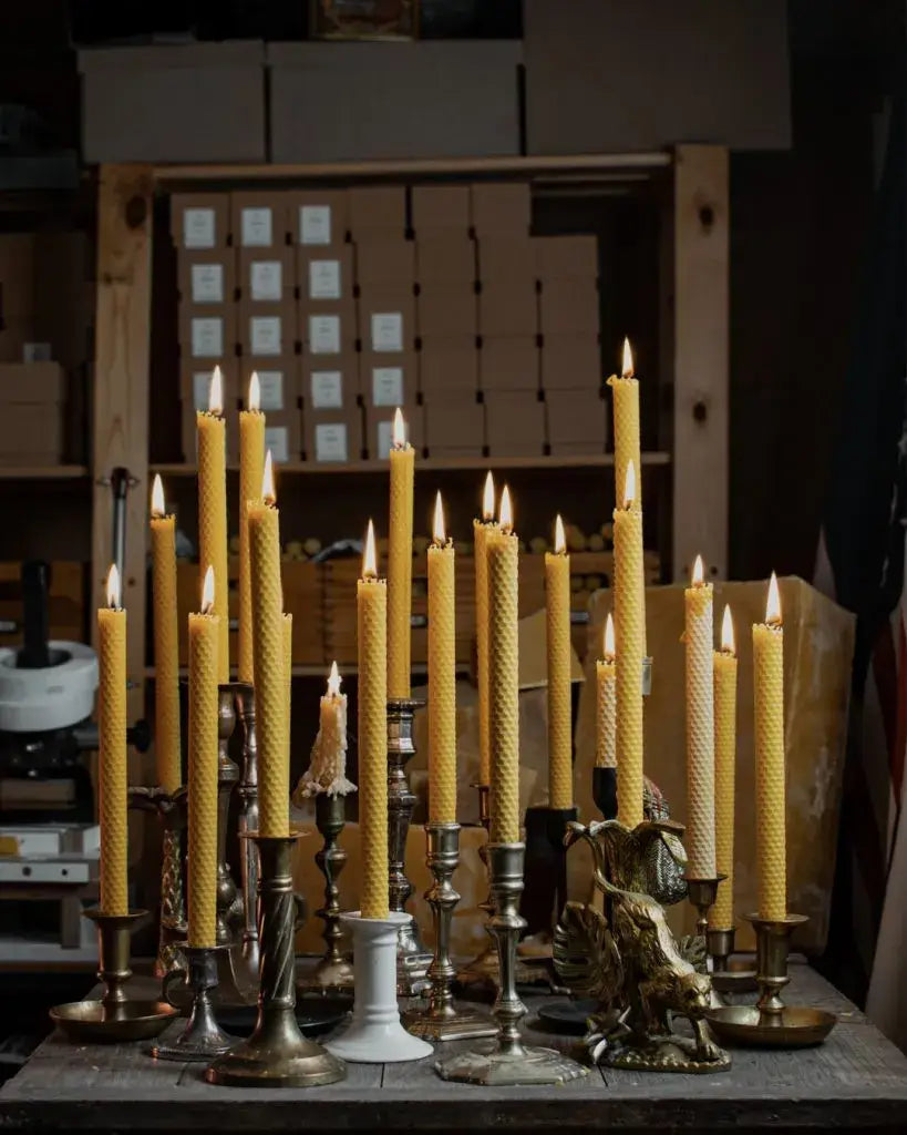Collection de bougies chandelles en cire d’abeille allumées dans divers supports pour instants précieux