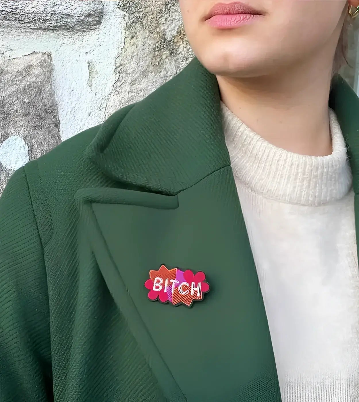 Broche Bitch : personne en manteau vert foncé avec pin aux couleurs vibrantes
