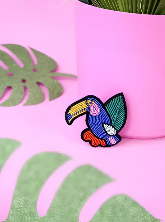 Broche toucan brodée vibrante avec corps bleu et bec jaune, touche tropicale facile à porter