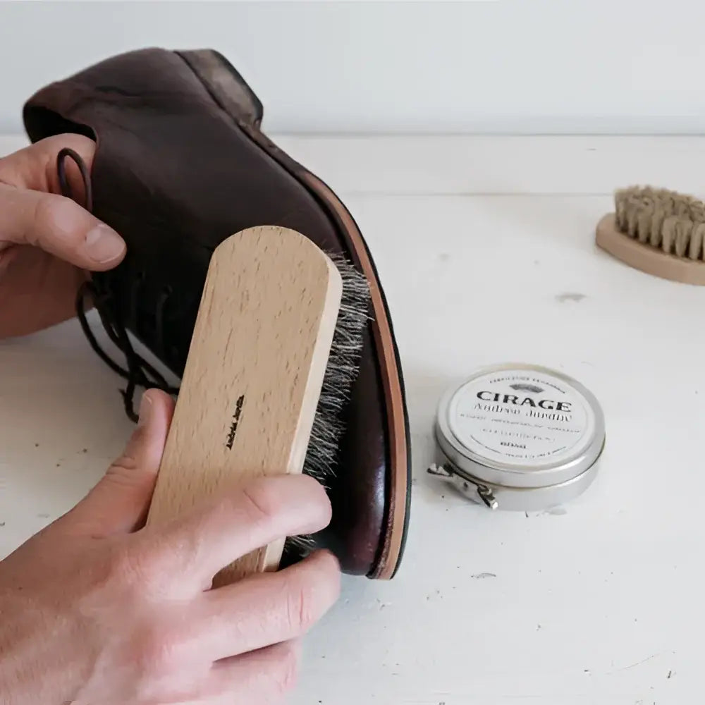 Mains polissant chaussure en cuir brun avec brosse à reluire en bois artisanale