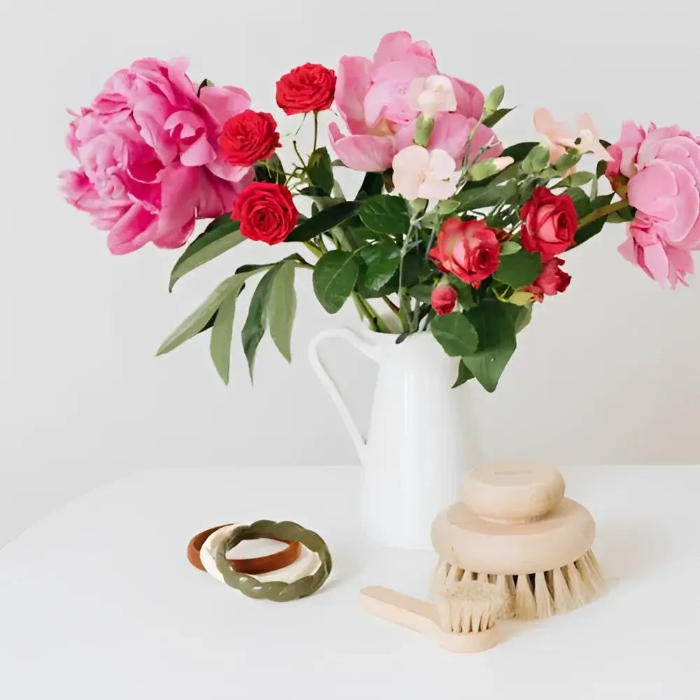 Bouquet vibrant de fleurs roses et rouges dans pichet blanc avec brosse corps