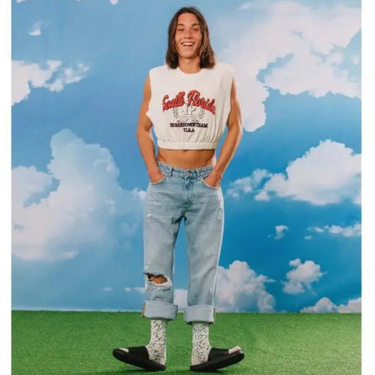 Personne en crop top blanc, jeans bleus, chaussettes fromage bleu, clin d’œil subtile