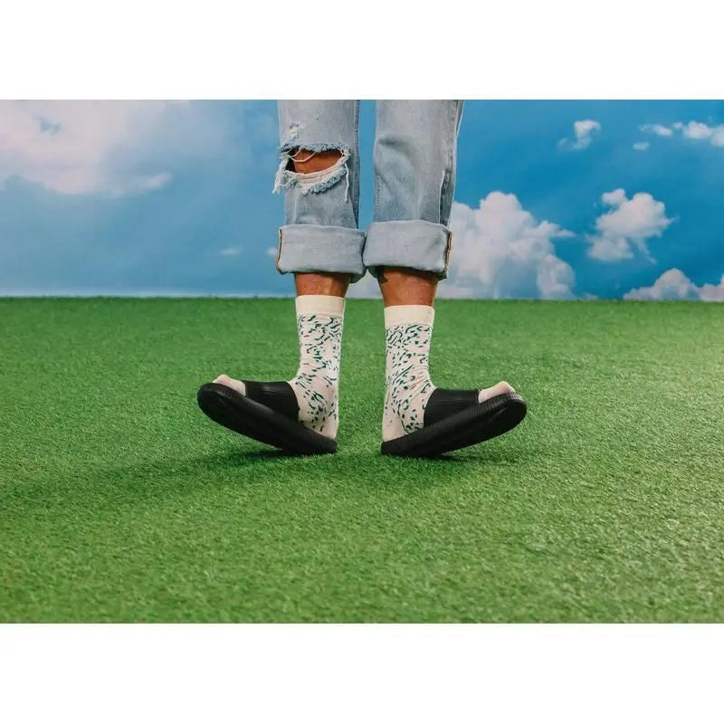 Personne en jeans déchirés clairs, chaussettes Chaussettes fromage bleu à motifs verts, sandales slides noires pour cadeau original et confort optimal