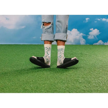 Personne en jeans déchirés clairs, chaussettes Chaussettes fromage bleu à motifs verts, sandales slides noires pour cadeau original et confort optimal