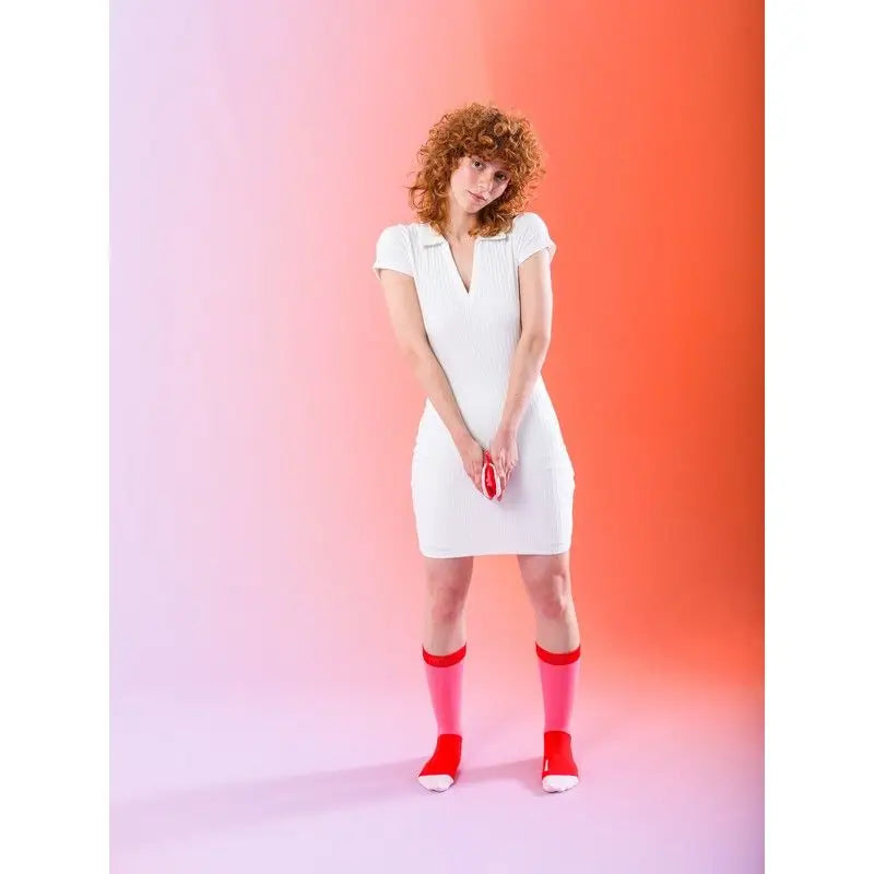 Femme aux cheveux roux bouclés en robe blanche et chaussettes viva la vulva audacieuses