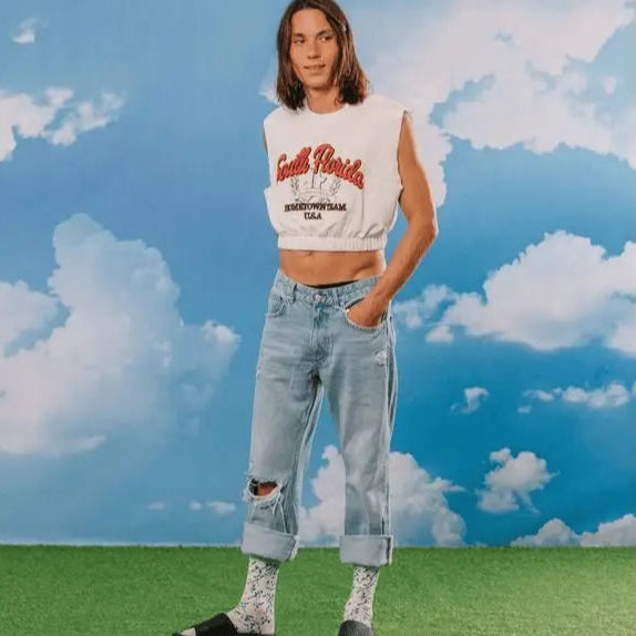 Personne en crop top blanc, jeans déchirés, chaussettes fantaisie blue cheese pour un confort optimal