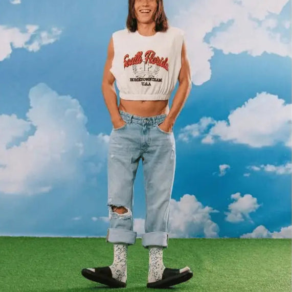 Personne en crop top blanc et jeans déchirés portant chaussettes blue cheese fantaisie