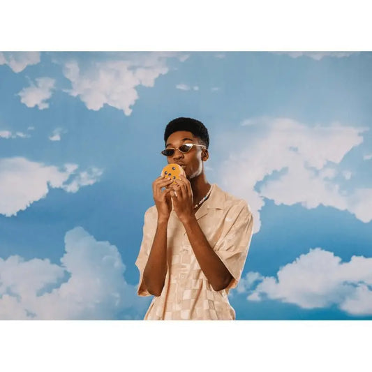 Jeune homme en lunettes de soleil mordant un cookie, chaussettes pancakes pour looks décalés