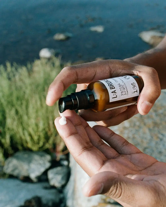 Main squeezing crème visage for peaux sensibles from pump bottle onto finger