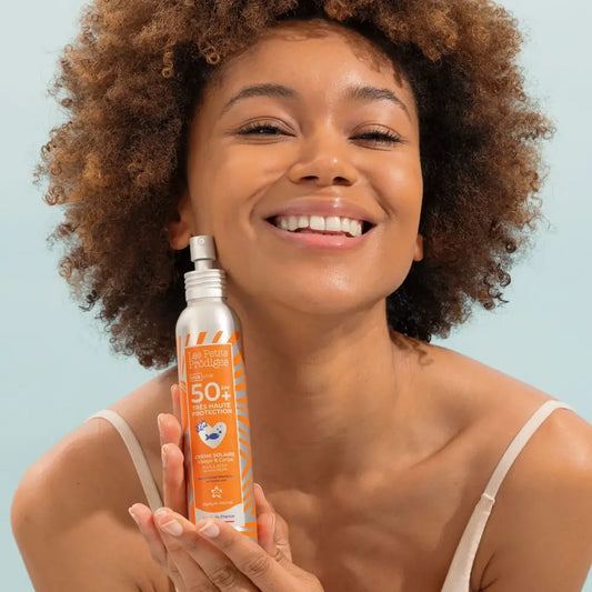 Femme tenant une crème solaire visage et corps spf50+ résistante à l’eau