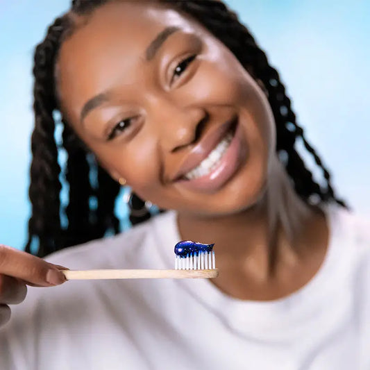 Jeune femme aux cheveux tressés avec dentifrice bleu pailleté pour sourire éclatant