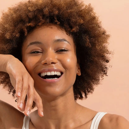 Femme souriante aux cheveux bouclés et peau éclatante avec dentifrice naturel menthe forte