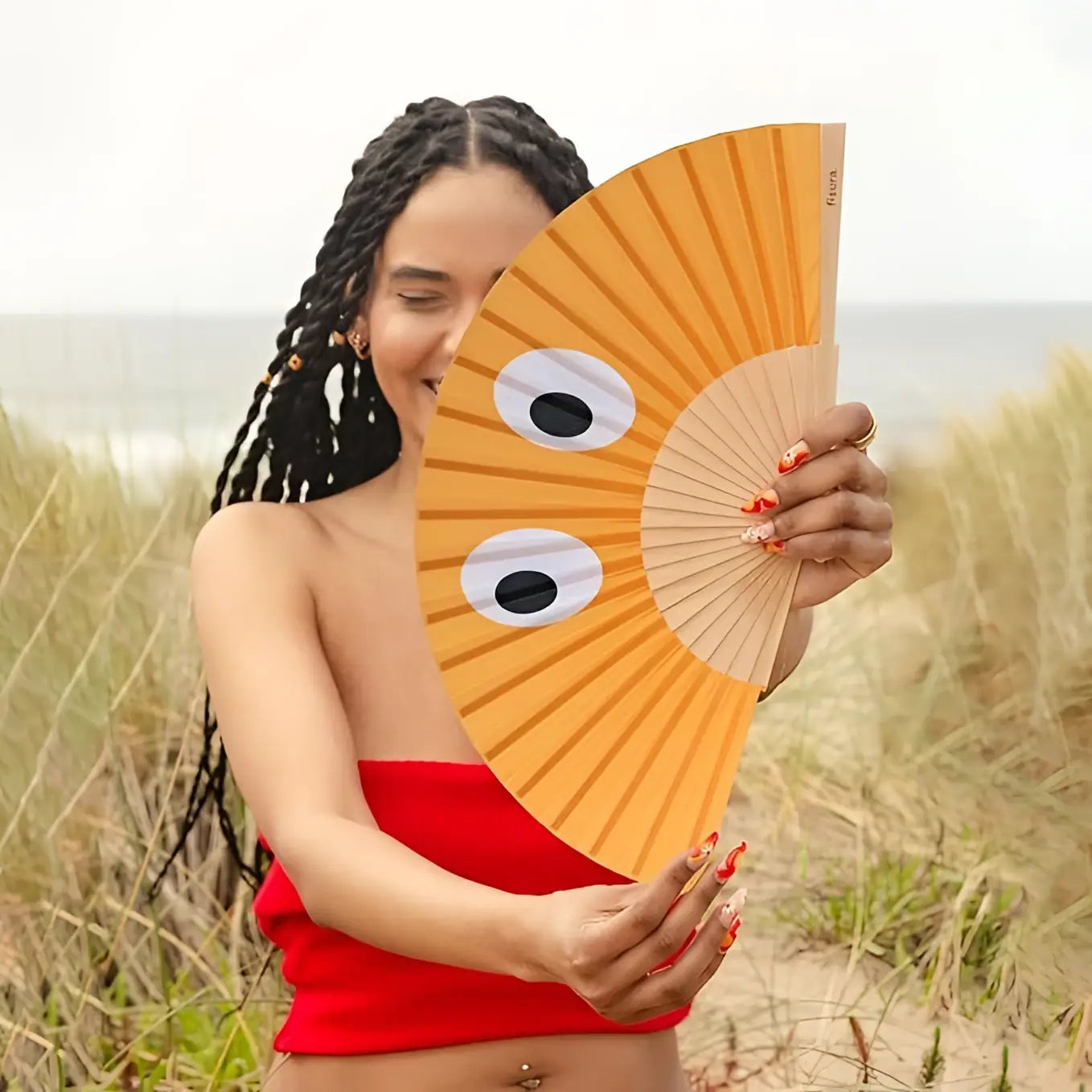 Éventail orange au design hypnotique avec yeux blancs et style unique