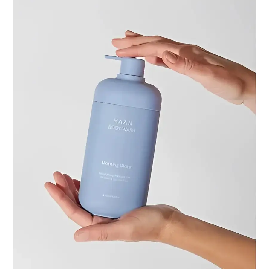 Gel douche hydratant aux probiotiques New Morning dans un flacon bleu held by two hands