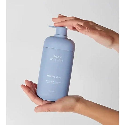 Gel douche hydratant aux probiotiques New Morning dans un flacon bleu held by two hands