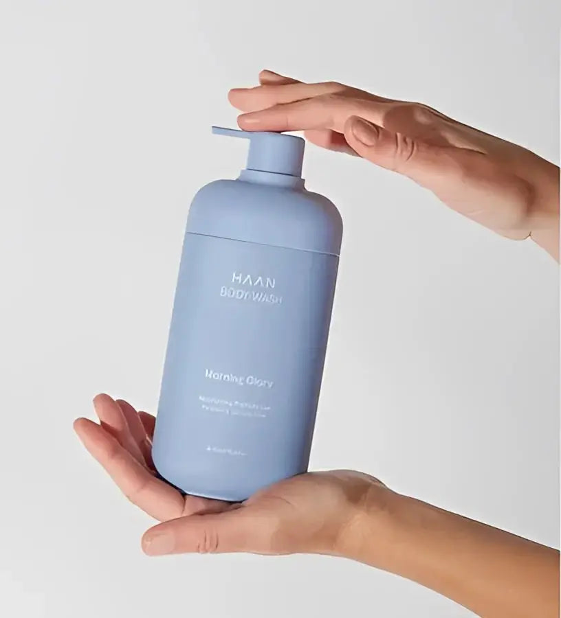 Mains tenant bouteille pompe bleu clair gel douche hydratant aux probiotiques New Morning