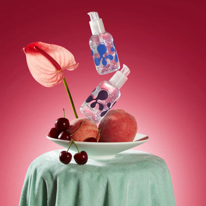 Deux bouteilles pompe Gel Joy Jolly au plaisir intense, texture soyeuse, au-dessus de fruits