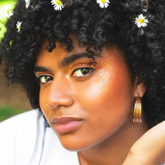 Femme aux cheveux ornés de marguerites avec Gel Pailleté Queen Du Desert pour un fini lumineux naturel