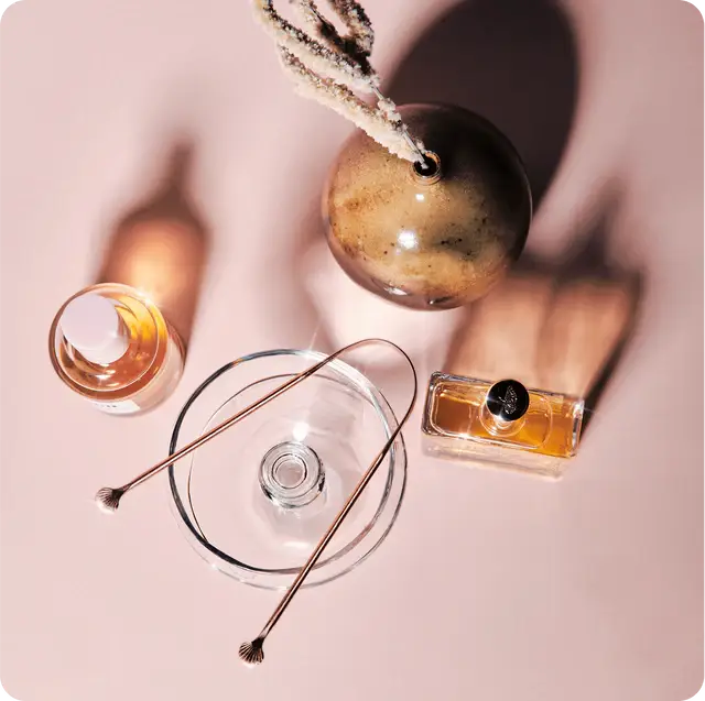 Collection de flacons de parfum et gratte langue Gratte Langue (poignées coquille) sur surface rose clair pour hygiène buccale