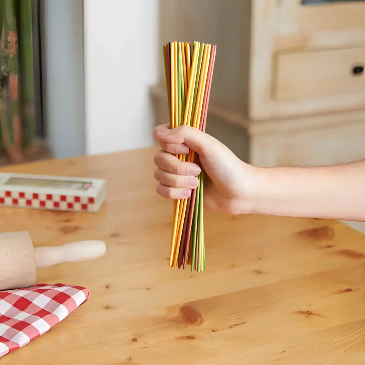 Main de jeu Mikadetti Bambou tenant spaghettis colorés