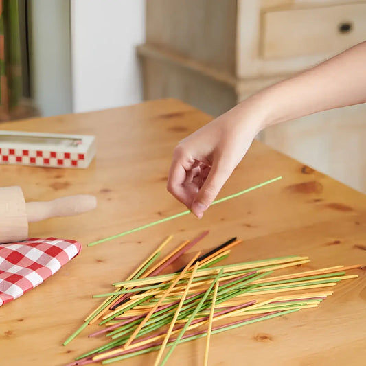 Main de jeu tenant bâton vert Mikadetti Bambou parmi spaghettis colorés