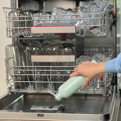 Main à verser liquide de rinçage innovant dans lave-vaisselle plein de vaisselle