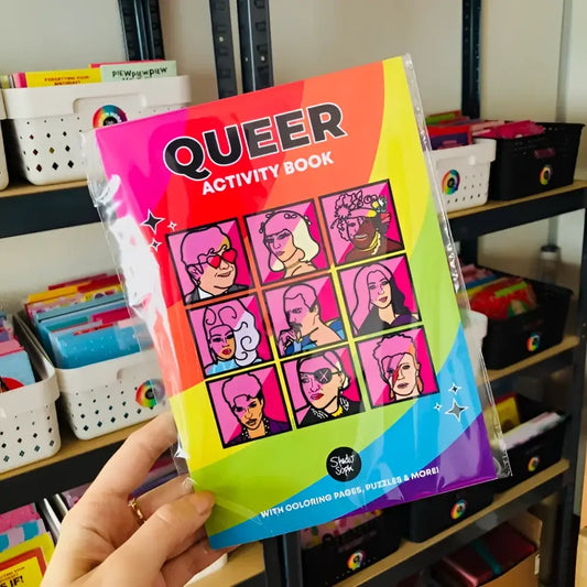 Cahier d’activités queer avec illustrations pop art de figures célèbres, contenu varié, emporté partout