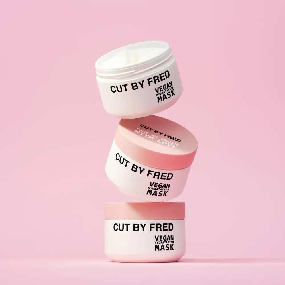 Trois pots empilés de Masque soin hydratant cheveux secs vegan en packaging blanc et rose