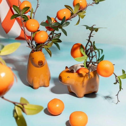 Mini vase capybara en céramique orange avec feuilles vertes et fruits orange, touche d’originalité