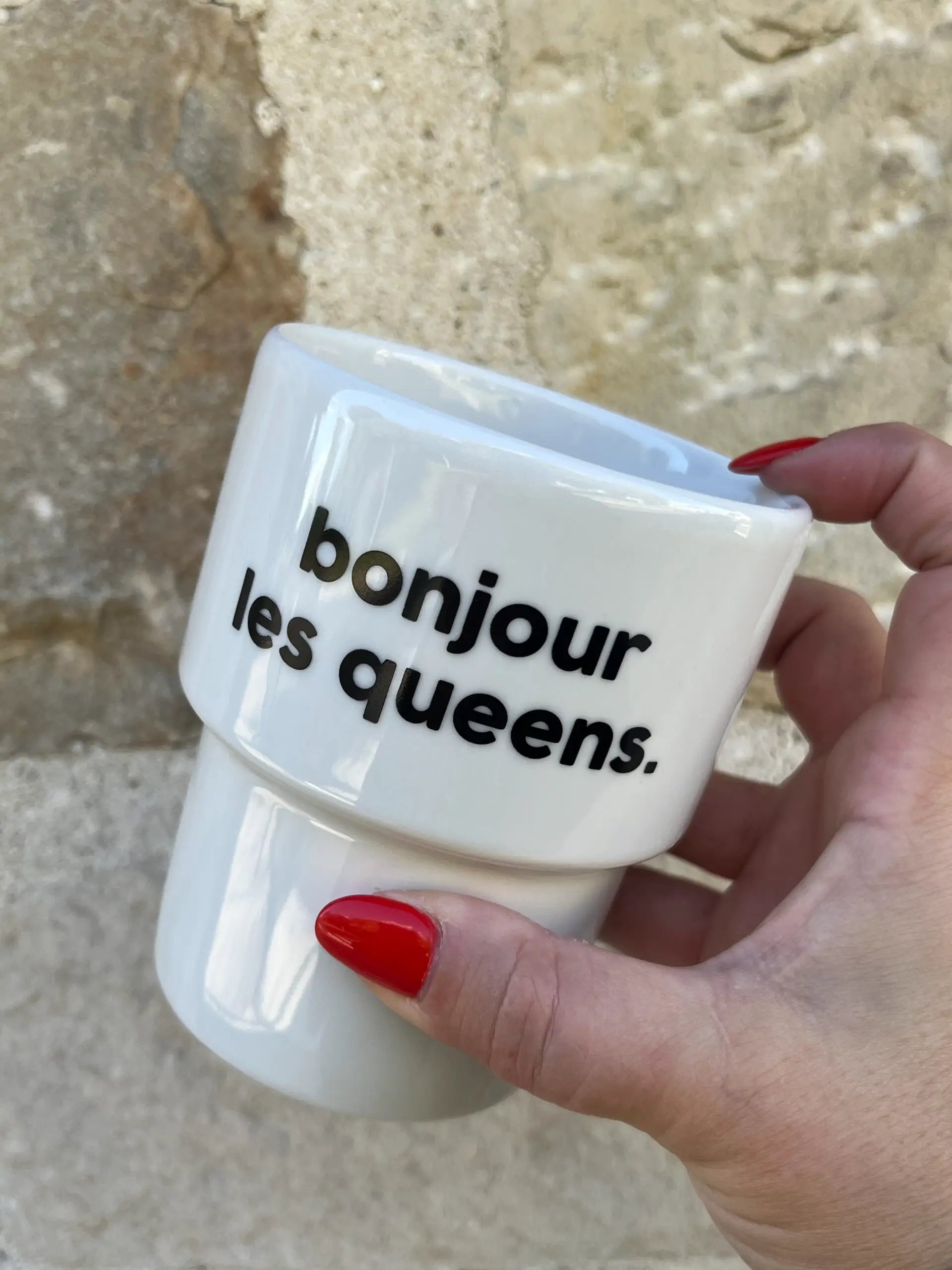 Mug bonjour les queens en céramique blanche, tenu par une main aux ongles rouges