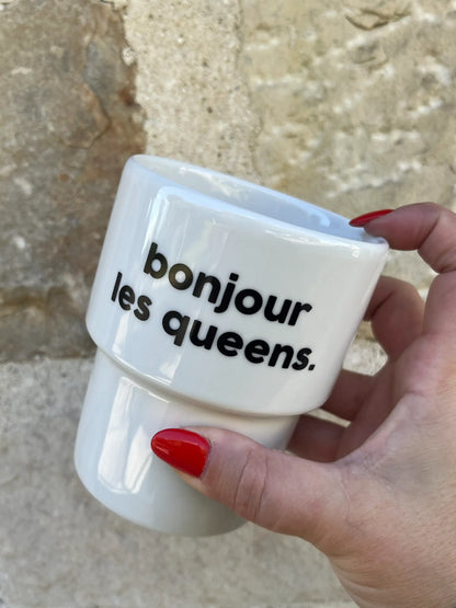 Mug bonjour les queens en céramique blanche, tenu par une main aux ongles rouges