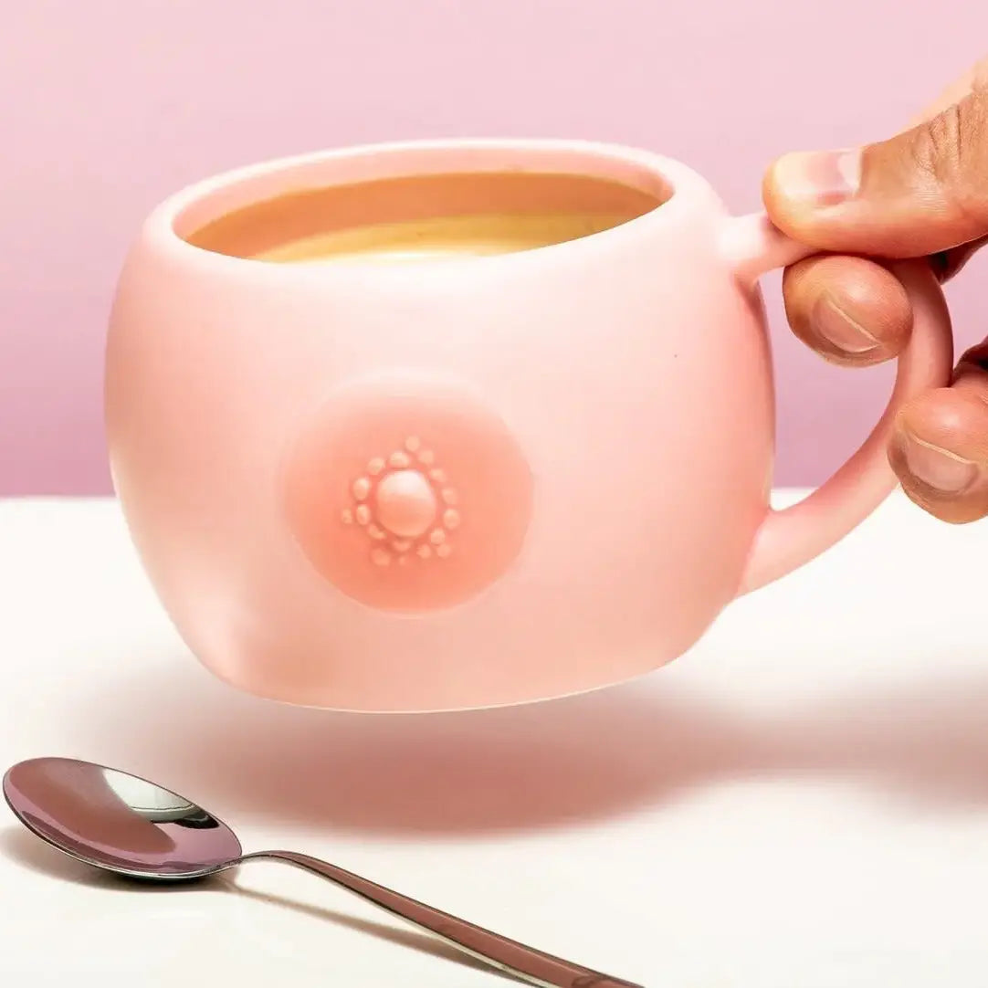 Main en tenant un mug audacieux en céramique résistante avec design mamelon rose pour pause café
