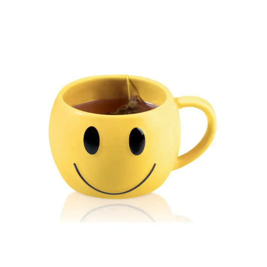 Mug smiley jaune avec poignée, rempli de liquide foncé et un sachet de thé